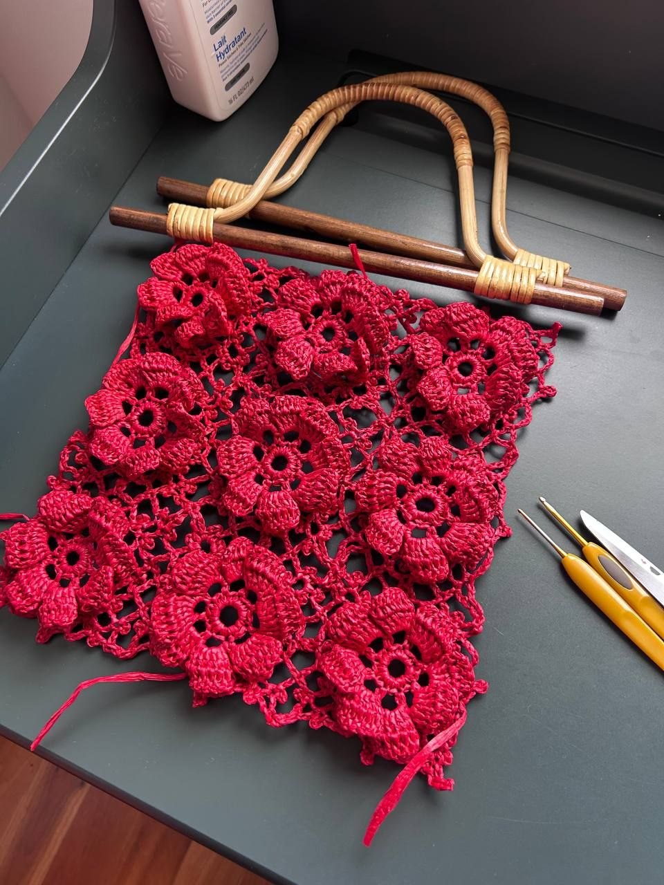 Red crochet flowers in progress with hooks
